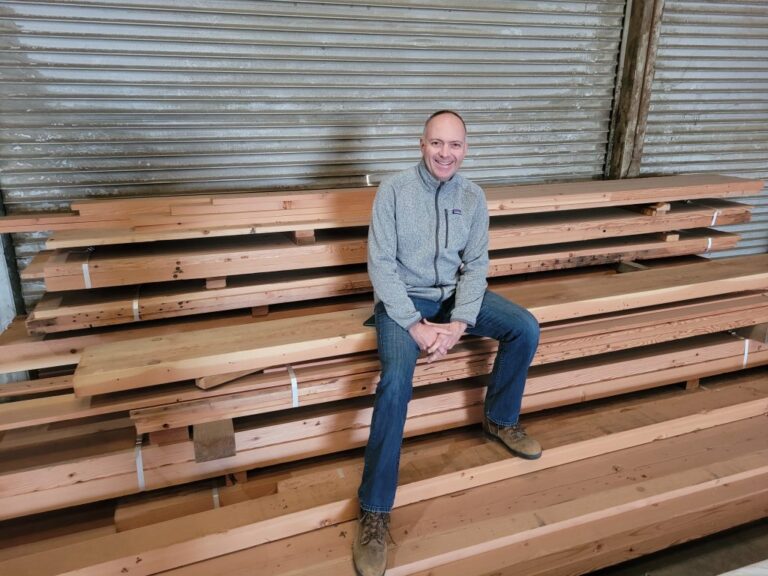 Urban Machine CEO & Co-Founder, Eric Law, sitting on a pile of reclaimed wood